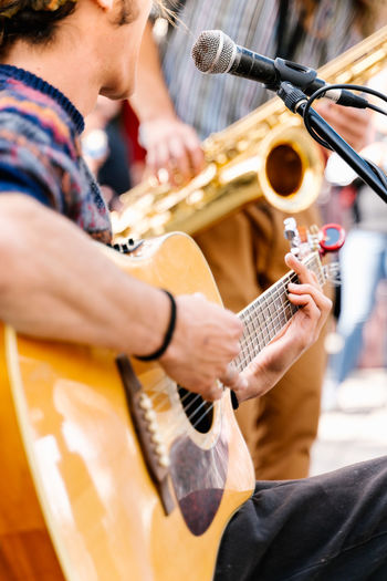 Selective focus on the hands of a young man playing a guitar in the street