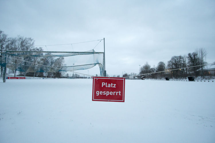Information sign on snow field against sky