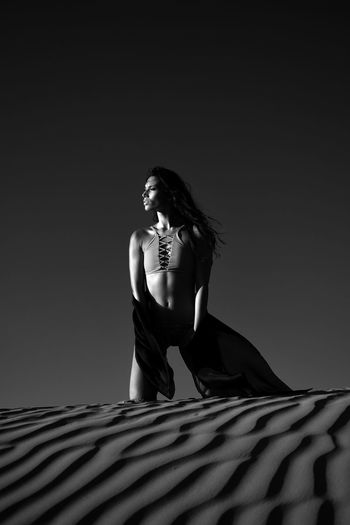 Woman looking away while standing on sand