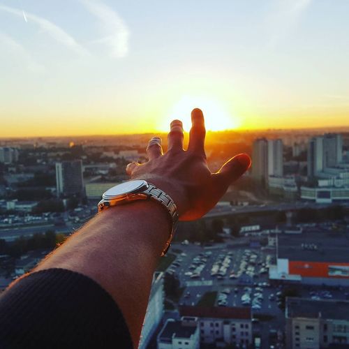 Optical illusion of man touching sun over cityscape
