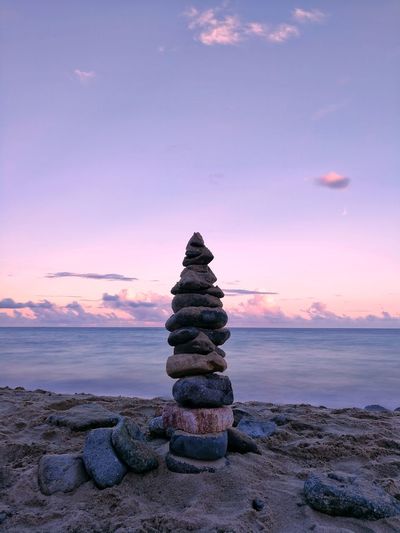 Stack of stones on shore during sunset