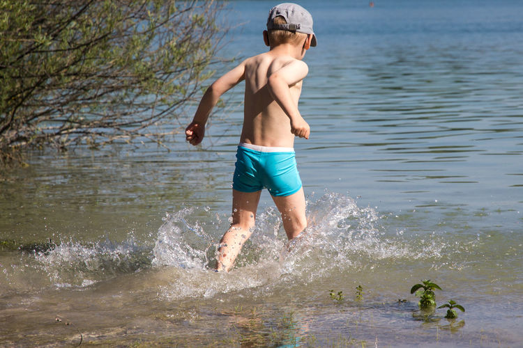 Shirtless boy wading in lake