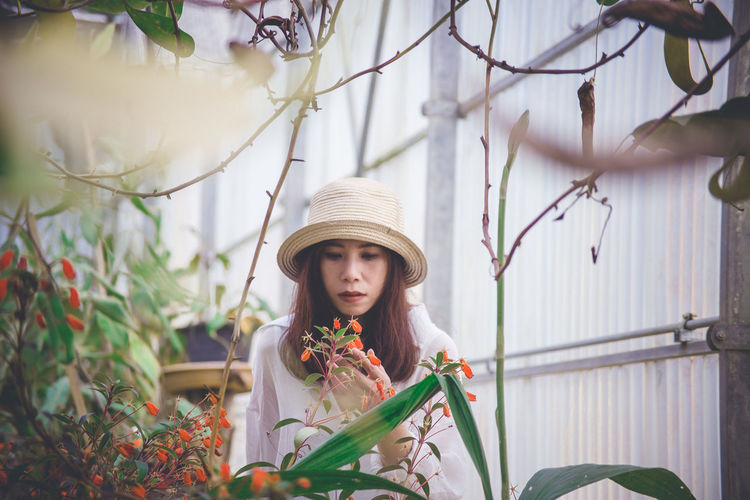 Portrait of young woman holding flower bouquet against plants