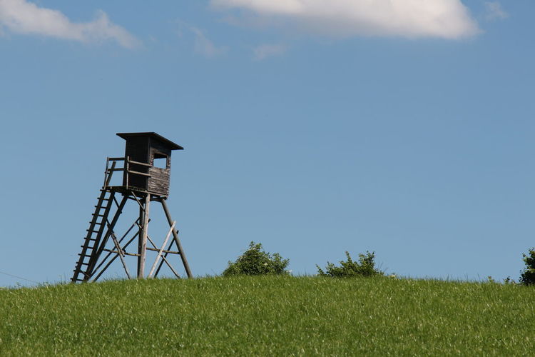 Low angle view of lookout tower on field against sky