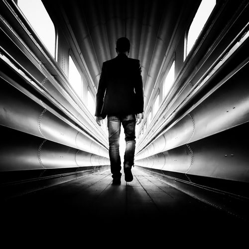 Full length rear view of man walking in corridor