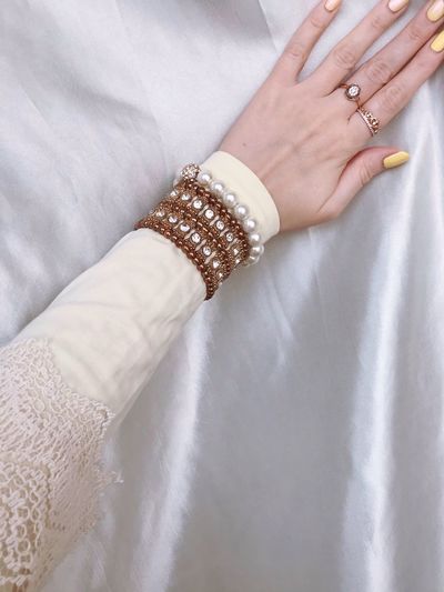 A hand of a woman wearing longsleeve and a bracelet