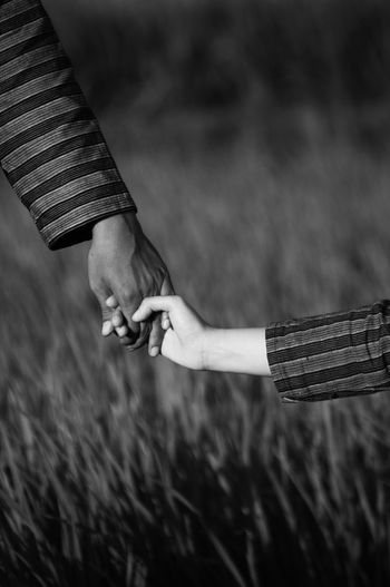 Midsection of couple holding hands on field