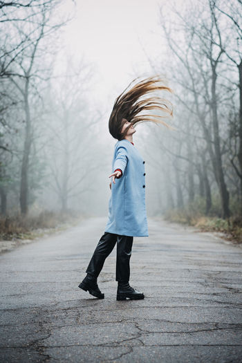 Alone young woman with long fluttering hair express emotions in forest