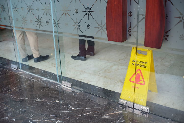 Information sign on floor against glass wall