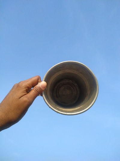 Low angle view of human hand against clear blue sky