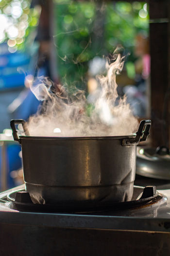 Metal pot boil soup on gas stove with smoke in thai kitchen. make food for breakfast.