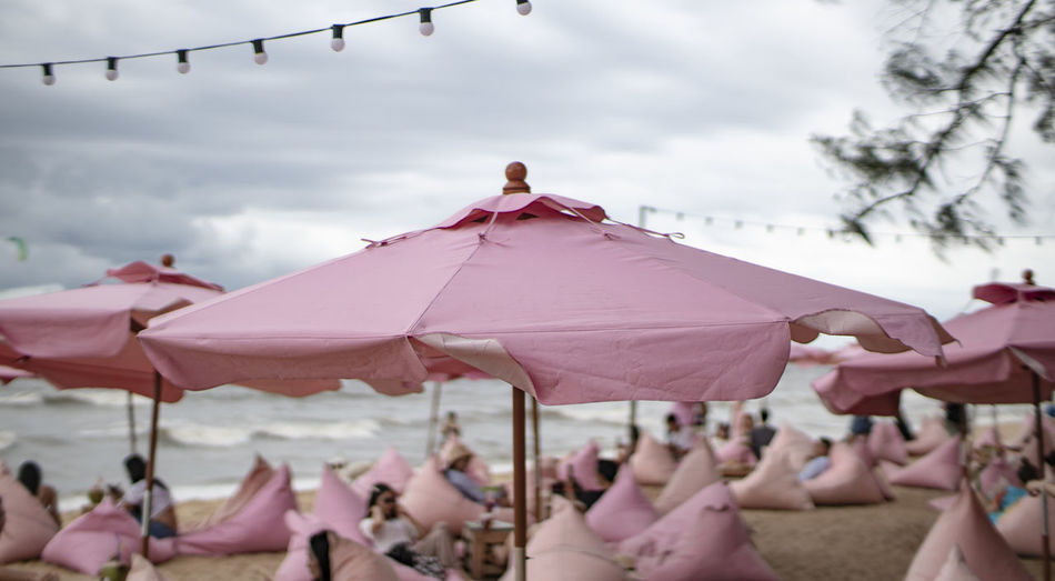 Group of people on pink umbrella against sky