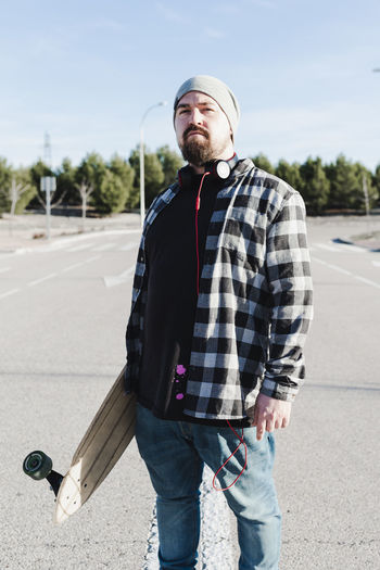 Close-up portrait of a modern man holding the longboard.