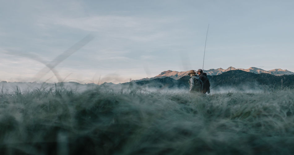 Man standing on field against sky flyfishing