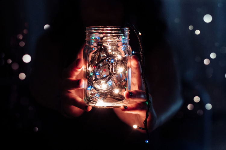 Woman holding illuminated fairy lights in jar during christmas