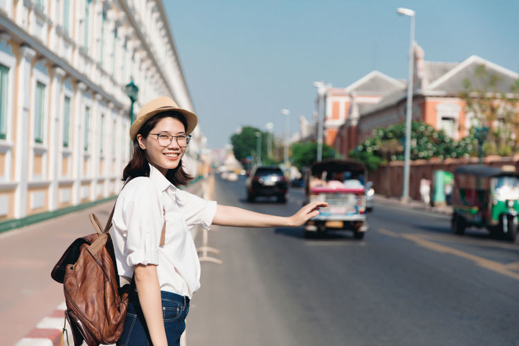 Portrait of smiling young woman standing on road in city