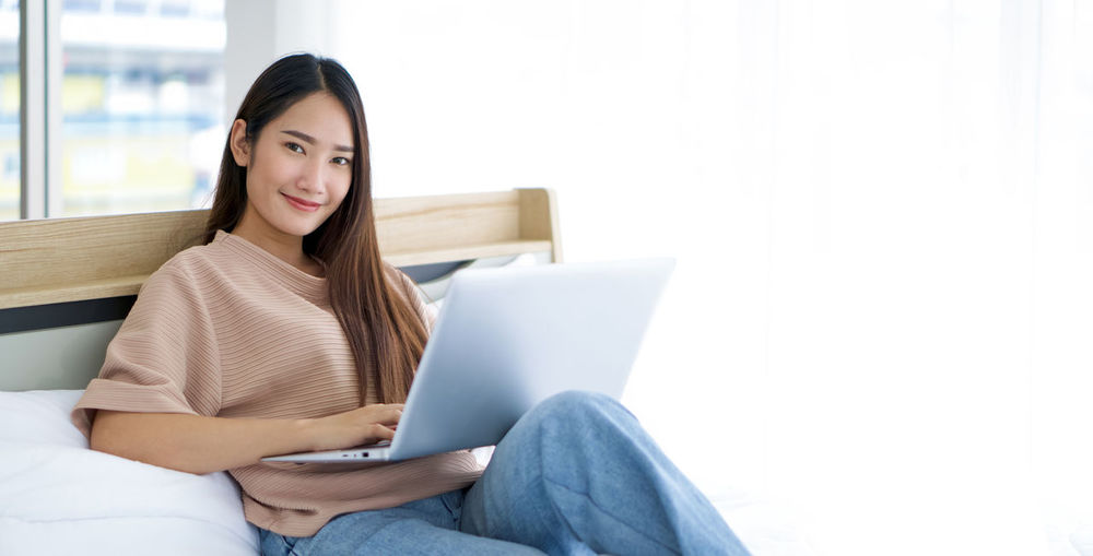 Young woman using phone while sitting on sofa