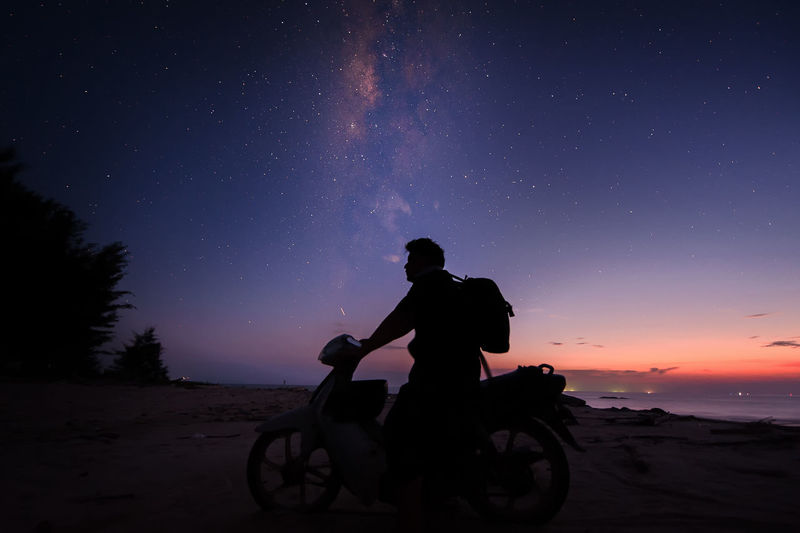 Silhouette man riding motorcycle against sky at night