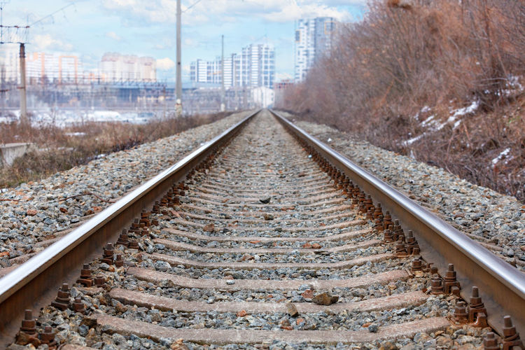 Parallel rails converging with each other against the backdrop of blurred cityscape in the distance.