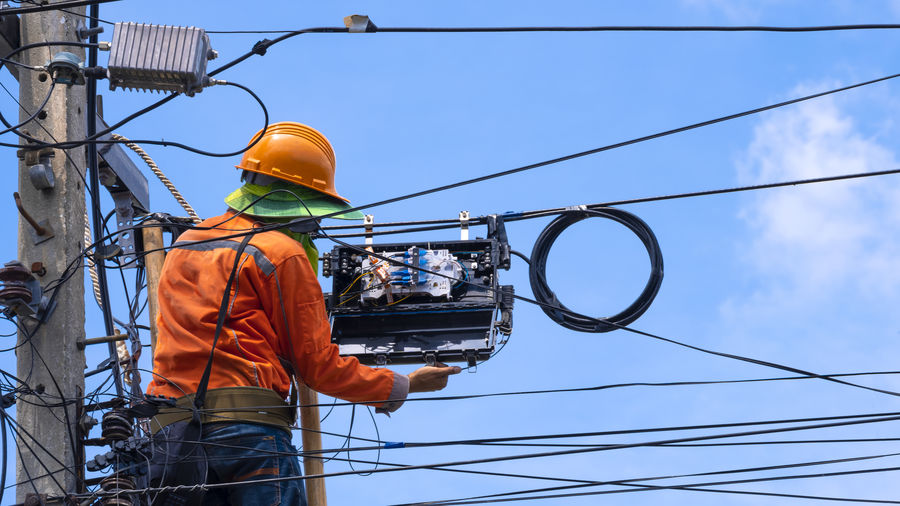Low angle view of electrician repairing power line