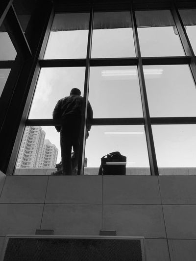 Low angle view of man standing on glass window