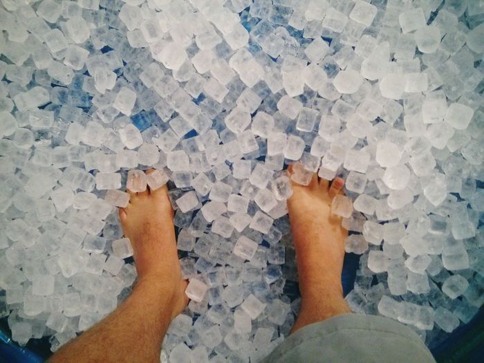 Low section of man standing on ice cubes
