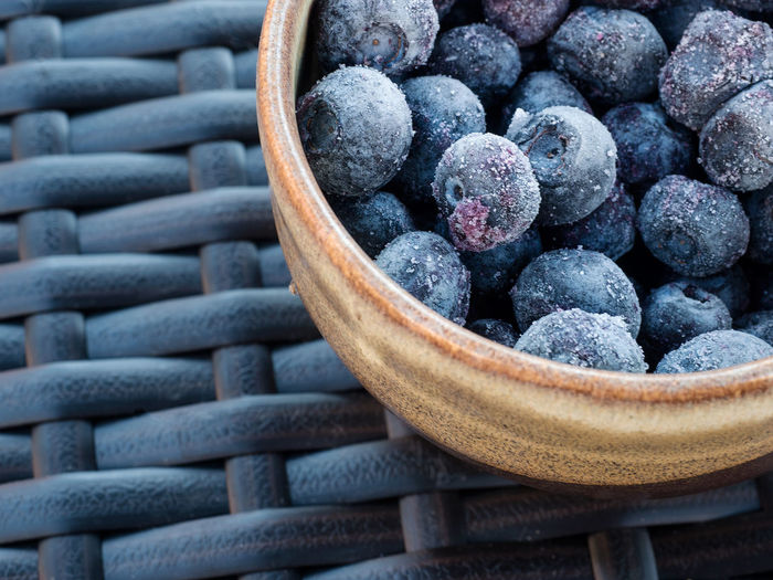 Close-up of blueberries in cup on wicker mat