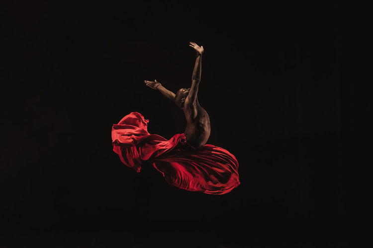 Male ballet dancer performing against black background
