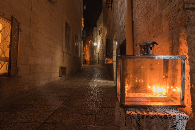 Hanukkah candles are lit, placed at the entrance to a narrow street in jerusalem, hanukkah
