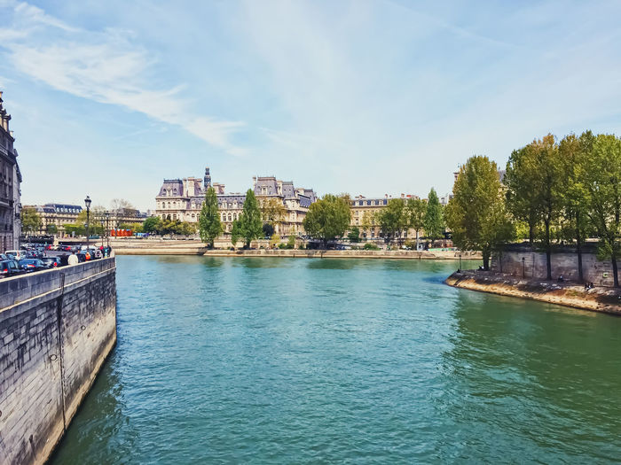 Buildings by river against sky