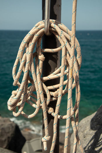 Close-up of rope tied on bollard by sea against sky