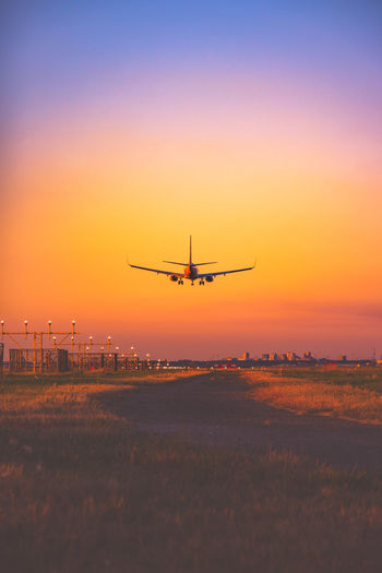 Airplane landing on runway during sunset