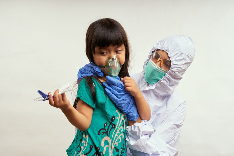 Doctor with girl wearing mask against white background