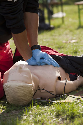 Midsection of woman learning cpr on grassy field
