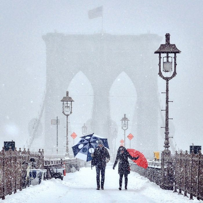 Man and woman walking at brooklyn bridge during snowfall