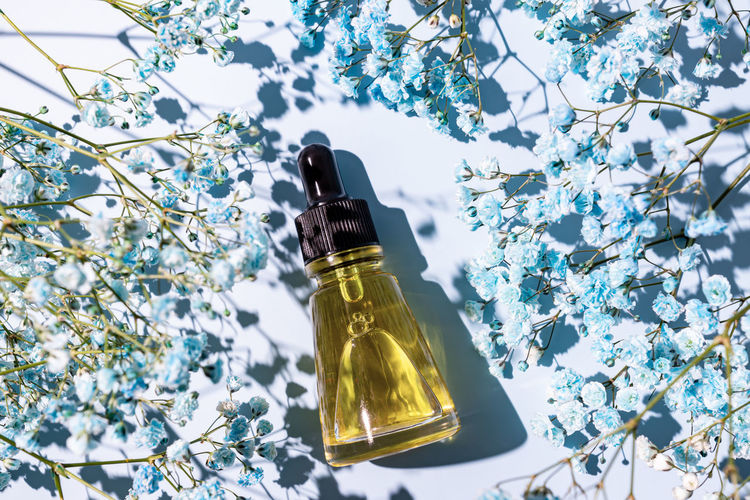 Beauty oil with natural ingredients on a blue background with flowers. skin care treatment concept.