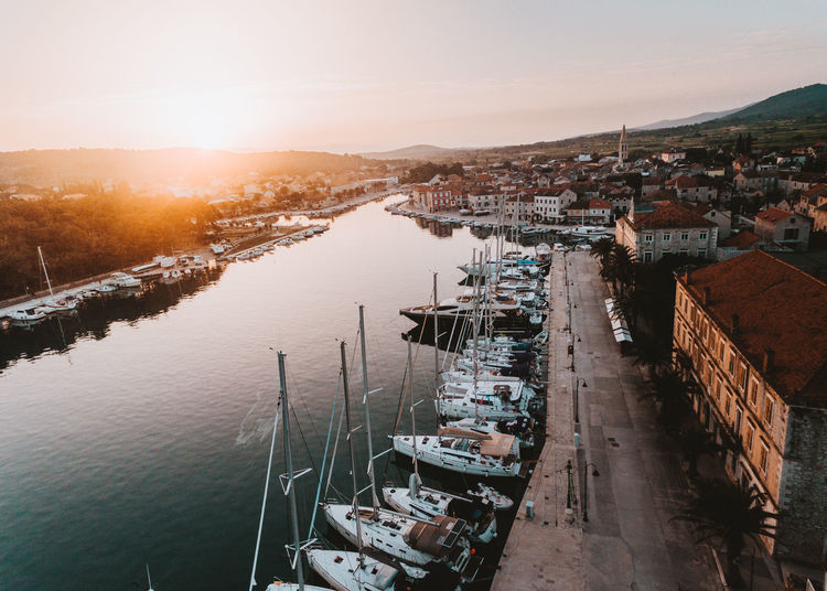 High angle view of boats moored at harbor against sky during sunset