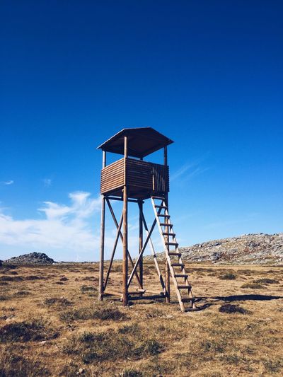 Lifeguard hut on field against clear blue sky