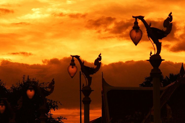 Silhouette sculpture against orange sky