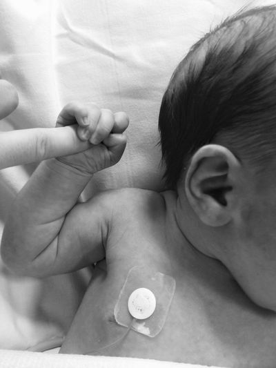 Cropped image of baby holding finger in hospital