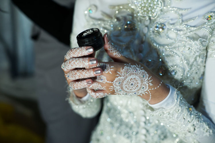 Midsection of bride wearing wedding dress while holding black container