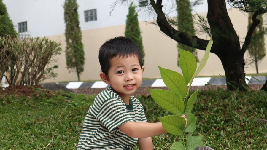 Portrait of cute boy holding plant outdoors