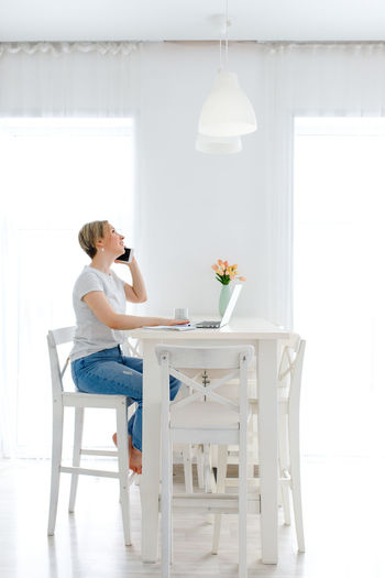 Side view of woman sitting on table at home