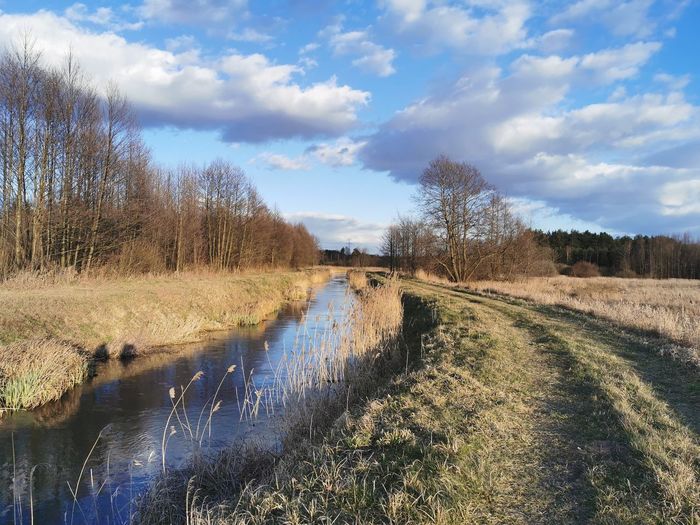 Canal amidst field against sky
