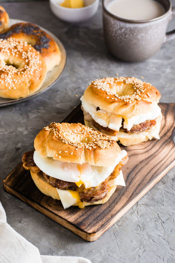 Bagels sandwiches with cheese, fried meat and poached egg on a board on the table
