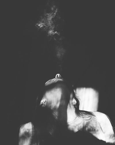 Close-up of mid adult woman smoking in darkroom