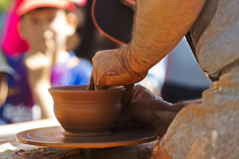 Midsection of potter making bowl in market