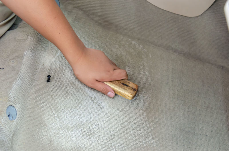 Cropped hand of person cleaning carpet