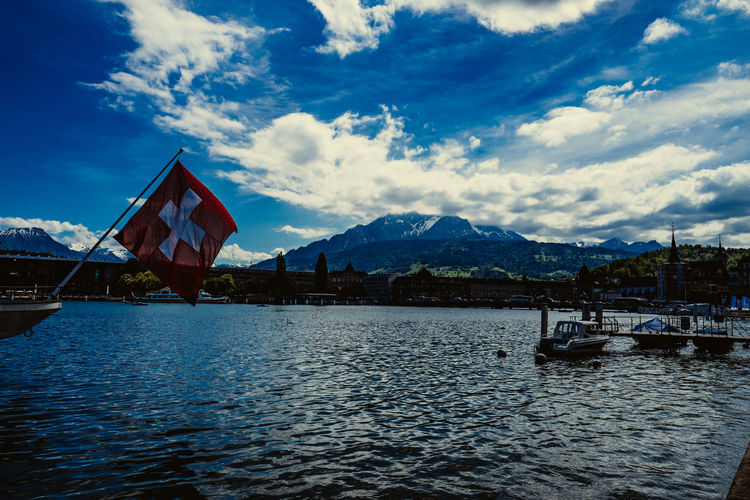 Swiss flag hanging over lake against sky