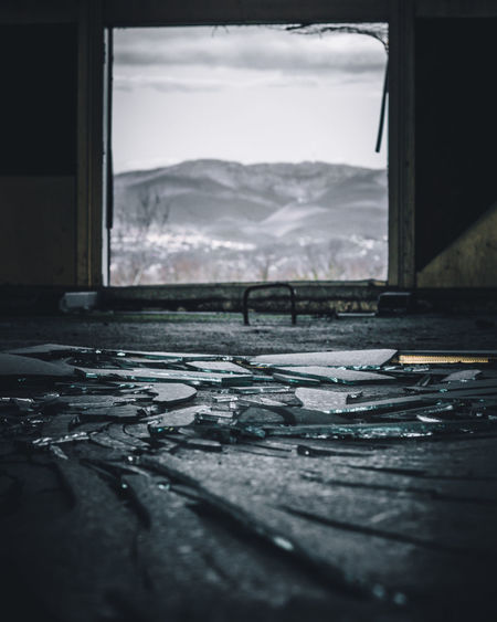 Close-up of broken glass window with mountain in the background